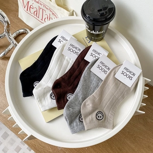 Gros plan de cinq paires de chaussettes basses en coton avec broderie smiley en plusieurs couleurs