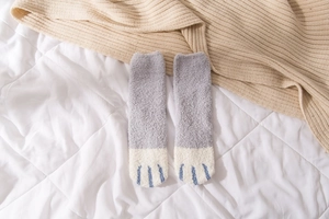 Close-up of thick coral fleece winter socks with cute blue embroidered cat paw patterns