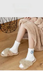 Detail of cross-strap plush slippers and fuzzy white socks with blue Swell embroidery