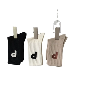 Trois paires de chaussettes en coton côtelé noir, crème et avoine avec broderie D
