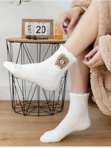 Close-up of thick white coral fleece socks featuring a cute plush 3D bear character