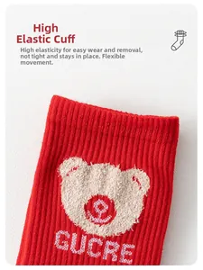 Detailed texture of red ribbed knit socks featuring a cute plush bear patch and elastic cuff