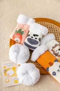 Close-up of fluffy animal socks in a wooden tray featuring thick fleece lining and embroidery