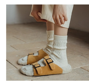 Mustard yellow suede Birkenstock style clogs with thick white faux fur lining and knit socks