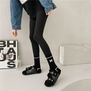 Detail of striped letter M embroidery on warm black crew socks with buckled faux fur slides