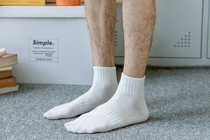 Close-up of white cotton ankle socks with ribbed compression texture on male model