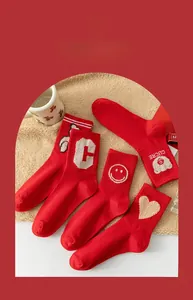 Close-up of four red mid-calf cotton socks with embroidery on soft beige plush