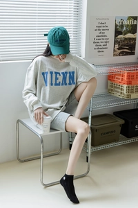 Gros plan d'un sweat-shirt gris avec imprimé VIENN bleu et casquette de baseball brodée