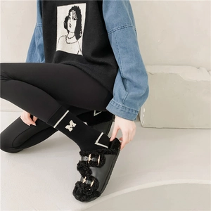 Detail of black faux fur slide sandals with gold buckles and letter M crew socks