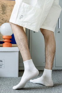 Detail of white ribbed cotton crew socks for men showing texture and elastic fit on model
