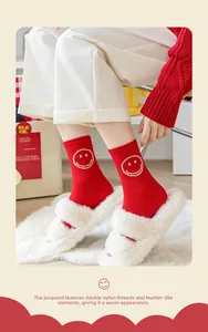 Detail of red knit crew socks featuring a white smiley face and soft feather yarn texture