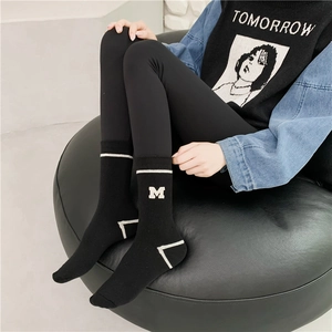 Detail of black sports crew sock with white striped embroidery and M letter logo