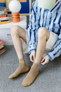 Detail of khaki crew socks with ribbed cuffs shown in a cozy indoor home setting