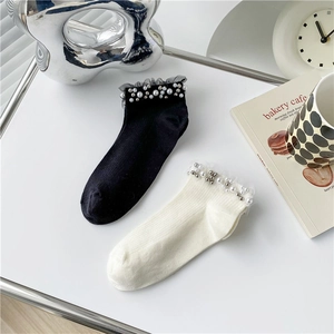 Damen-Socken mit zarten Spitzenrüschen und eleganten Perlenverzierungen in Nahaufnahme
