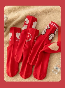Detail showing red mid-calf socks with cute bear and heart embroidery on soft wool background