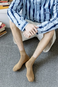Detailed close-up of light brown ribbed cotton socks for men shown on a grey rug