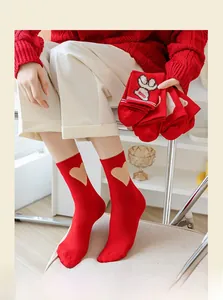 Close-up of red cotton crew socks with heart patterns and ribbed cuffs in a home setting
