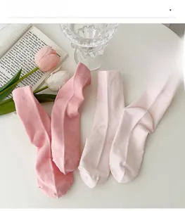 Detail view of soft pink cotton socks set arranged with lifestyle home decor props