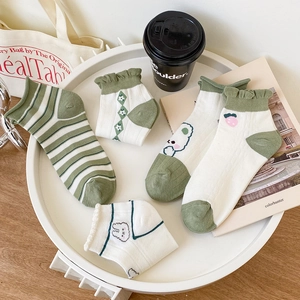 Flat lay of forest-themed green and white patterned cotton socks in a white tray