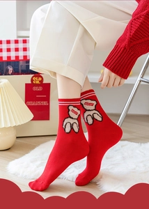 Detail of red crew socks featuring a cute bear patch with white stripes on the cuffs