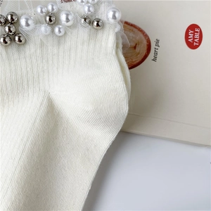Nahaufnahme weißer Baumwollsocken mit zarter Spitze und elegantem Perlenbesatz