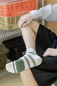 Detail of white cotton low-cut men socks featuring green stripes and breathable knit texture