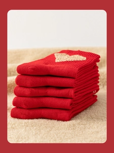 Close-up of 5 pairs of red knit socks with beige heart patterns and ribbed texture