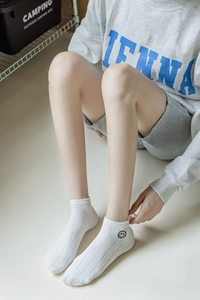 Détail de chaussettes basses blanches en coton avec broderie smiley noire et texture côtelée