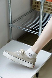 Détail de chaussettes blanches en coton avec motif smiley noir brodé sur le côté