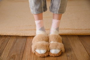 Detail of warm brown faux fur slippers and plush thick socks on cozy home flooring