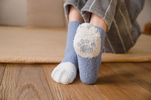 Close-up of cozy cat paw pattern coral fleece socks worn on a warm home carpet