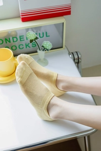 Detail of light yellow mesh boat socks with breathable texture and low-cut design