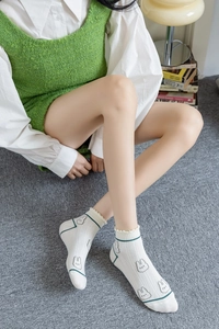 Close-up of white cotton socks with green cartoon rabbits and ruffled edge detailing