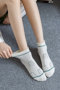 Detail of white cotton ankle socks with wavy cuff and cute rabbit pattern on grey carpet
