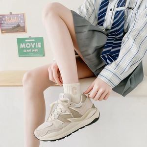 Detail of light beige ribbed cotton socks with letter C embroidery and retro sneakers