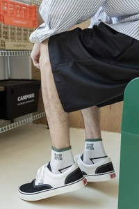 Detail of white cotton crew socks with green trim and M embroidery for casual city boy style