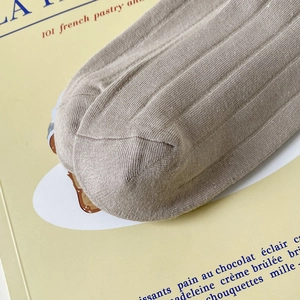 Détail de chaussettes en coton tricoté beige montrant la texture côtelée et la couture