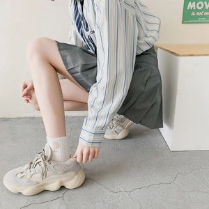 Detail shot of beige chunky sneakers paired with white embroidered P-letter crew socks