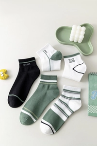 Macro detail of breathable cotton ankle socks featuring sporty letter embroidery patterns