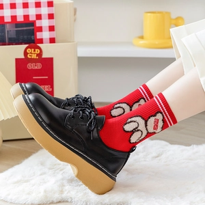 Red cotton crew socks with teddy bear print worn with black platform loafers on white rug
