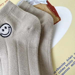 Gros plan détaillé d'une chaussette en coton kaki avec broderie de visage souriant