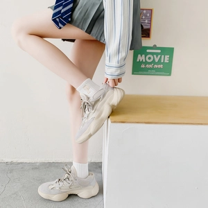 Detail of chunky beige and grey sneakers styled with white embroidered crew socks