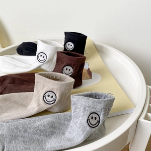 Détail de chaussettes en coton colorées avec smileys brodés et texture côtelée