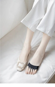 Detail of five-toe half-palm socks in black knit worn with rhinestone buckle flats