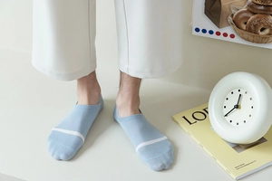 Detail of light blue low-cut cotton sock with white stripe on a person wearing white trousers