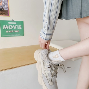 Detail of grey dad sneakers and white cotton socks with brown 'P' embroidery