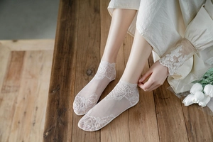 Close-up of white lace mesh ankle socks with rose embroidery on model feet