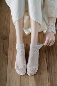 Close-up of white lace sheer socks with elegant rose floral embroidery for summer