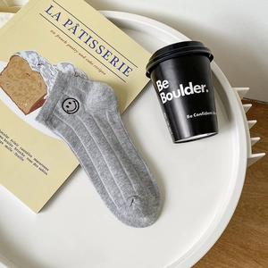 Socquettes en coton gris clair avec broderie sourire mignon sur un plateau décoratif