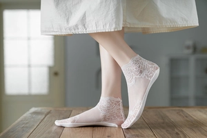 Detail of white floral lace ankle socks featuring breathable rose pattern texture